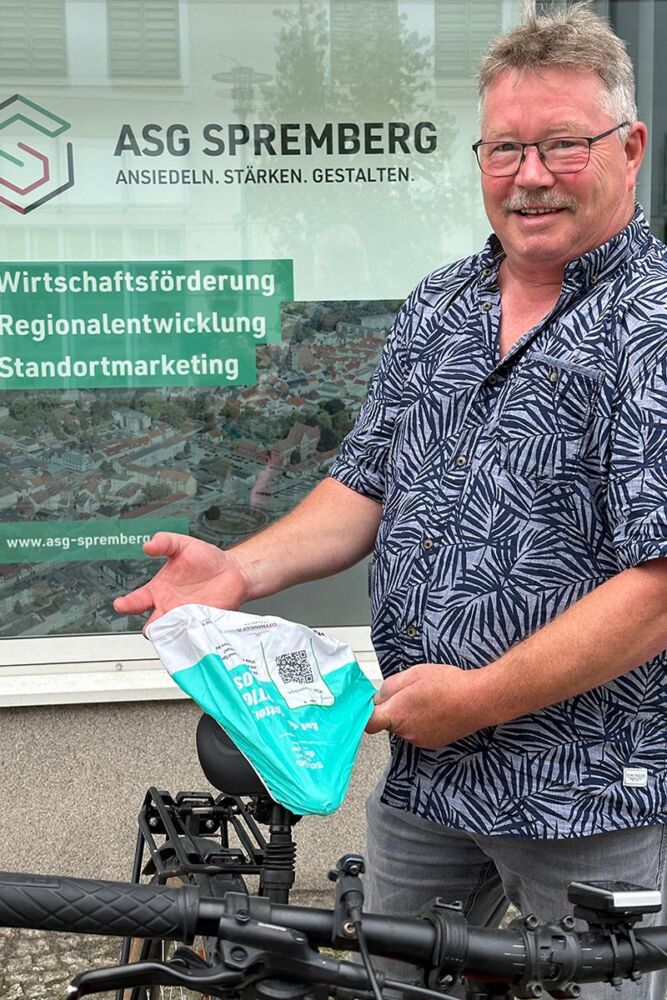 ASG-Mitarbeiter Siegfried Jung mit einer wetterfesten Satteldecke. Auf diser der QR-Code zum Spremberg Account bei Komoot.