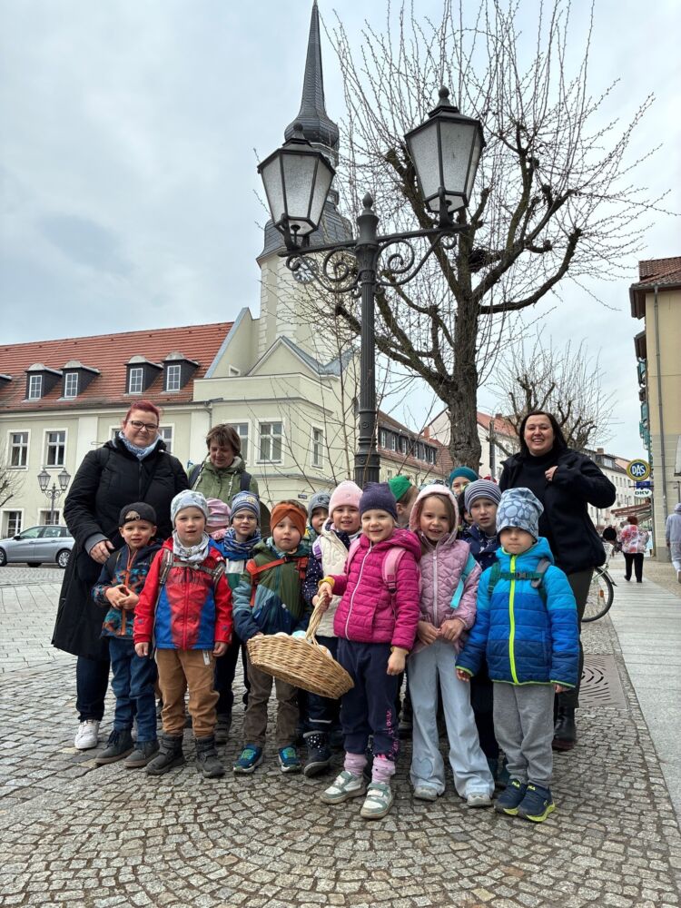 Kita-Kinder hängen im März 2026 bunte Ostereier in der Innenstadt von Spremberg auf.
